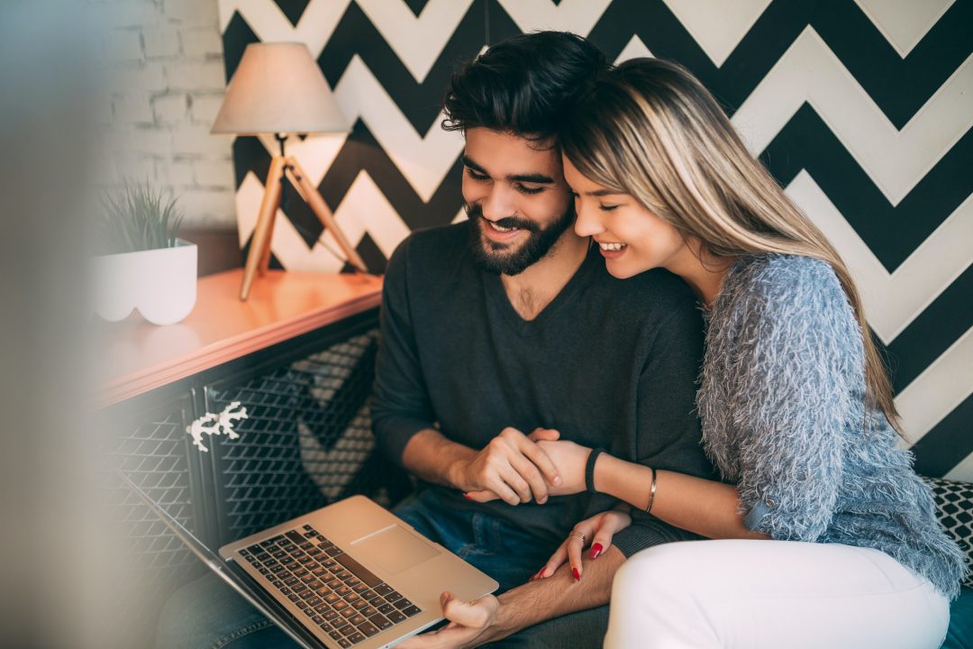 happy couple watching something on laptop at cafe surfing on internet or video chatting 1 1