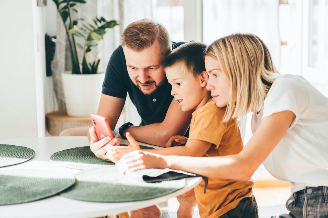 happy family with son using mobile apps together at home